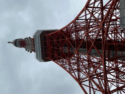 Low-angle view of the red and white Tokyo Tower against a grey sky.