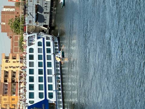 Small rowboat with two men paddling beside a large white Nile cruise ship docked on the river