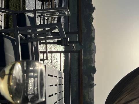 Relaxing deck scene with sparkling Nile waters, silhouetted hills and a glass of white wine at sunset