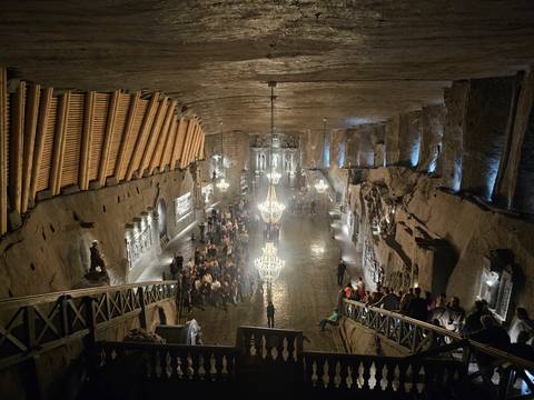 Illuminated chandelier hall carved from salt deep within the Wieliczka Salt Mine, bustling with visitors.