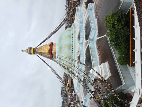 The golden spire and white dome of Boudhanath Stupa draped with colorful prayer flags dominate the Kathmandu skyline.