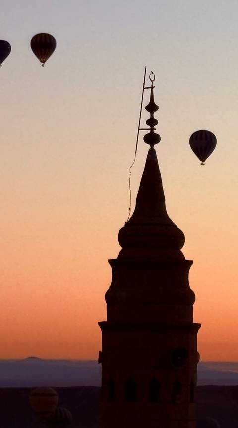 silhouette of tower spire with distant hot-air balloon at orange sunrise sky