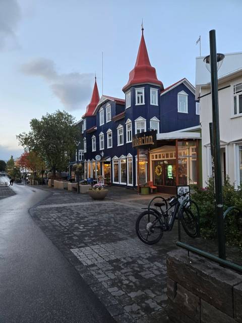 Charming main street of Akureyri lined with colourful wooden buildings, shops and bicycles at dusk.
