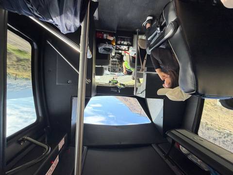 Passengers seated in a tour bus gaze forward as the vehicle winds along a scenic highway.