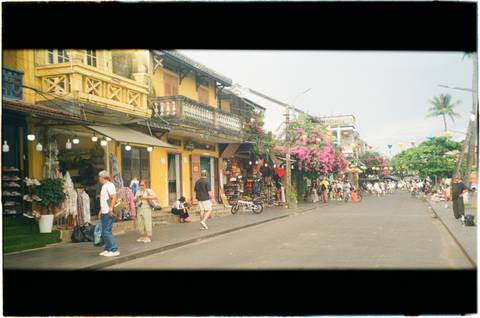 Film-style street photo of Hoi An ancient town with yellow shophouses and lanterns.