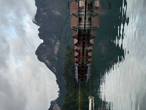 Floating wooden bungalows reflect in the calm emerald waters of a mountain lake at dawn.