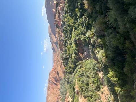 Green terraced valleys and a small town nestled among Morocco’s red hills under a clear sky.
