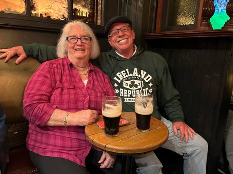 Smiling older couple enjoying pints of Guinness at a cozy pub table.