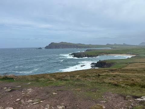 Rugged Atlantic coastline with crashing waves, cliffs and distant headlands under cloudy sky.