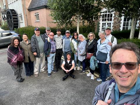 Large tour group posing together outdoors in casual jackets and smiles.