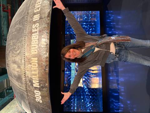 Woman posing enthusiastically under a giant display inside the Guinness Storehouse.