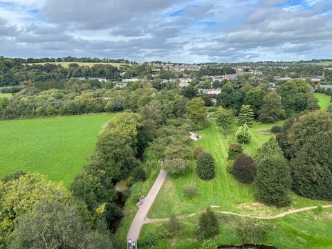 Expansive green parkland and small town viewed from above on a cloudy day.