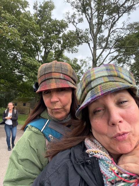 Playful close-up selfie of two women wearing patterned wool caps.