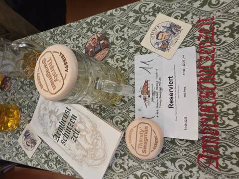 Beer stein with coaster and reservation slip on a wooden table at Oktoberfest.