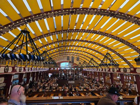 Wide view of a beer hall interior with striking yellow striped ceiling and hanging wreaths.