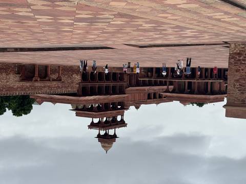Large sandstone palace courtyard with scattered tourists exploring.