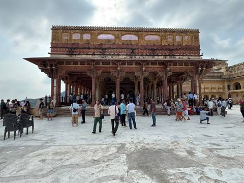 Crowded courtyard inside Amber Fort with ornate columns and tourists.