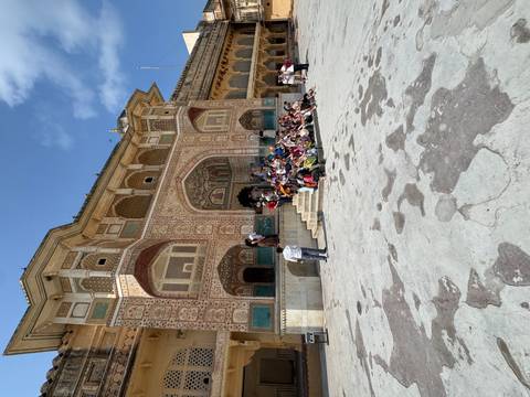 Large tour group posing on the decorative Ganesh Pol gate at Amber Fort.