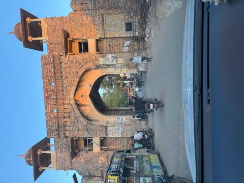 Vehicles and pedestrians passing through a rustic stone gate at dusk.