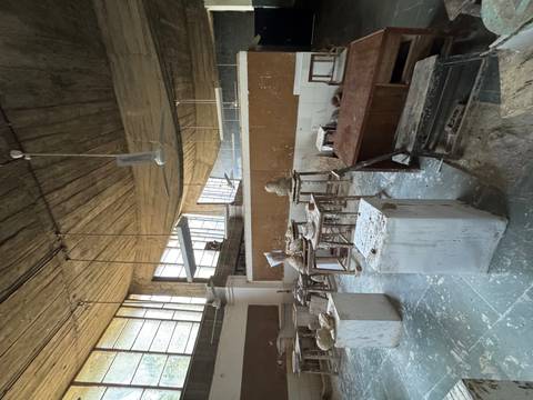 Dusty art studio interior with clay sculptures, work tables and large windows letting in diffused light.