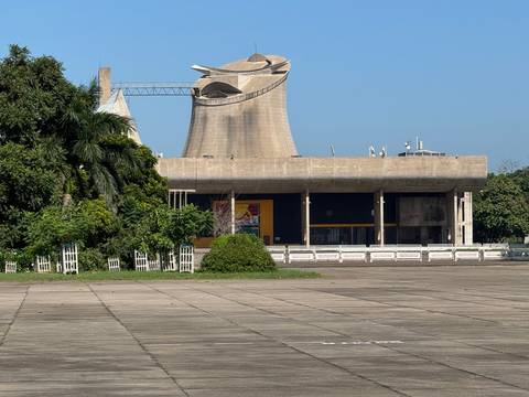 Distinctive concrete tower and assembly building of Chandigarh framed by lush greenery on a sunny day.