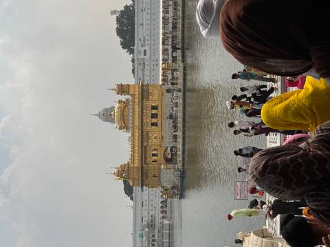 Golden Temple shimmering across the holy pool with crowds of worshippers in colourful headscarves in the foreground.