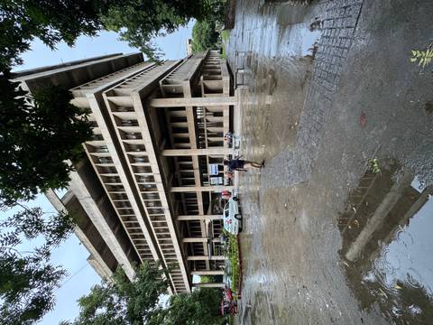 Tall concrete office block in Chandigarh with rainy forecourt as a lone pedestrian crosses.