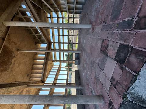Interior of an unfinished concrete tower with tall pillars and ribbon windows overlooking countryside.