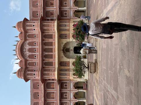 Entrance of Jaipur’s City Palace with flowering pots and tourists walking into the ornate hall.