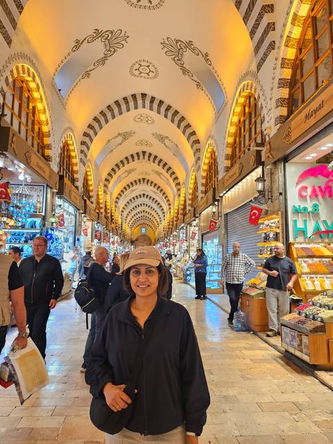 Traveller poses inside Istanbul’s ornate Spice Bazaar with vaulted ceilings and lively stalls.