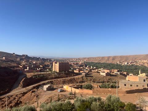 Terracotta-coloured village houses scatter across a dry hillside overlooking a narrow green valley.