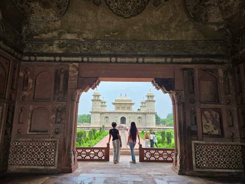 View of Itmad-ud-Daulah mausoleum framed by the ornate archway of a red-sandstone gateway.
