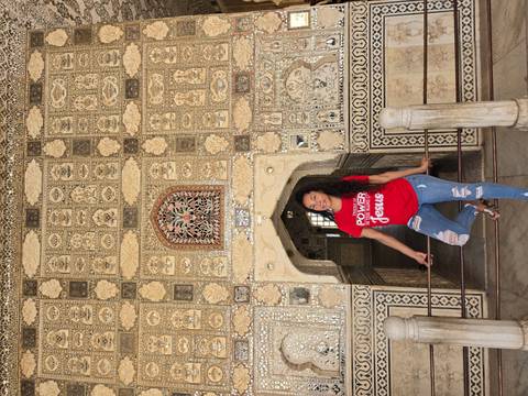 Traveler poses inside the shimmering mirror-inlaid Sheesh Mahal chamber.