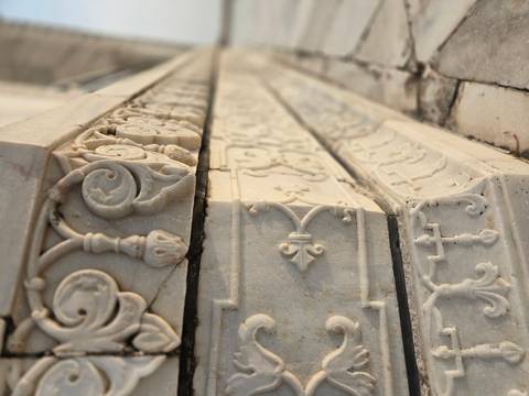 Close-up of intricate white marble carvings and inlay work on a Mughal monument.
