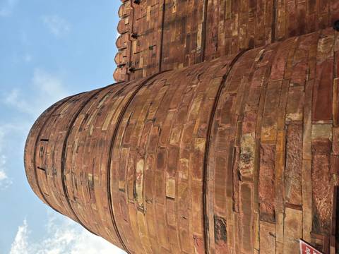 Upward angle of a massive red-sandstone bastion and battlements against a blue sky.