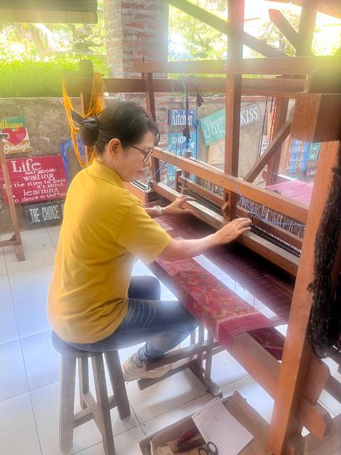 Woman operates a wooden handloom inside a local weaving workshop.