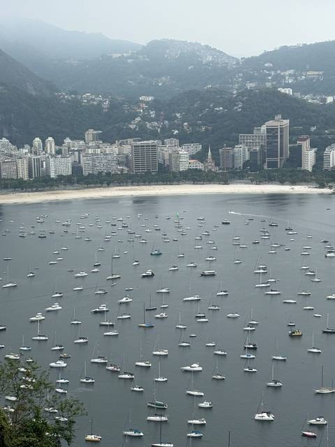 High vantage of Botafogo Bay peppered with anchored boats against Rio skyline.