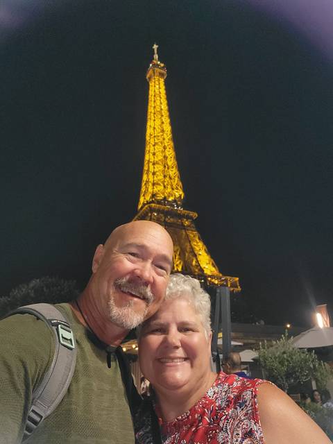 Night selfie of a couple in front of the illuminated Eiffel Tower.
