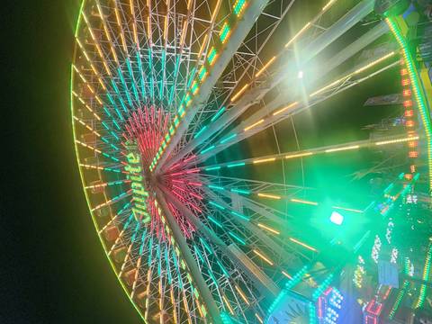 Upward view of a brightly lit ferris wheel at night with the word 'Jupiter' glowing.