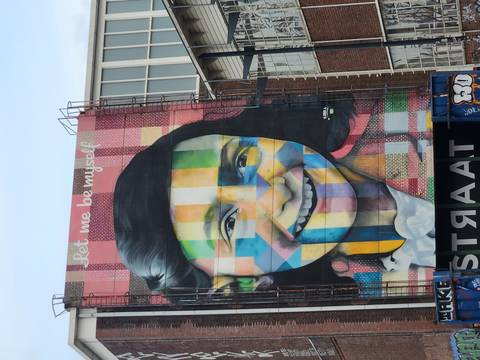 Colorful mural of Anne Frank on a tall building at STRAAT museum.