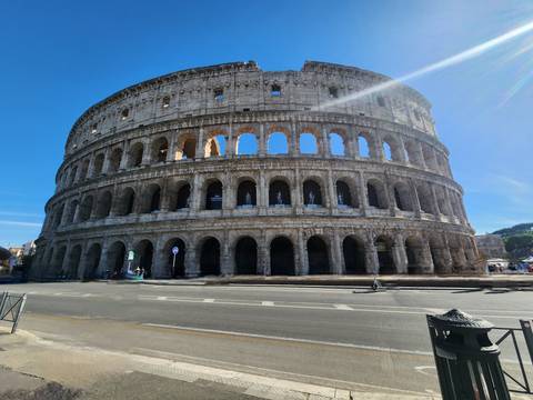 Wide daytime view of the Colosseum against a clear blue sky in Rome.