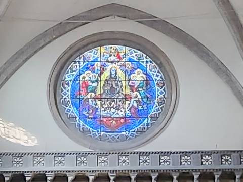 Soft, out-of-focus photo of a circular stained-glass window inside a church.