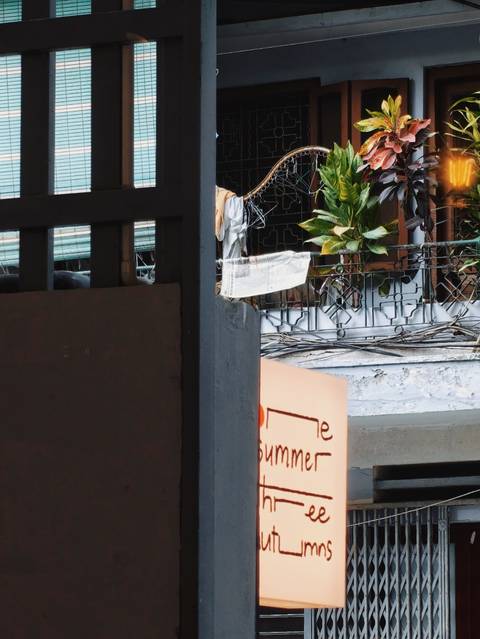 Partial exterior view with wires, plants and an obscured sign; content unclear.