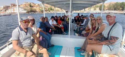 Tour group seated on an open boat cruising a wide river.