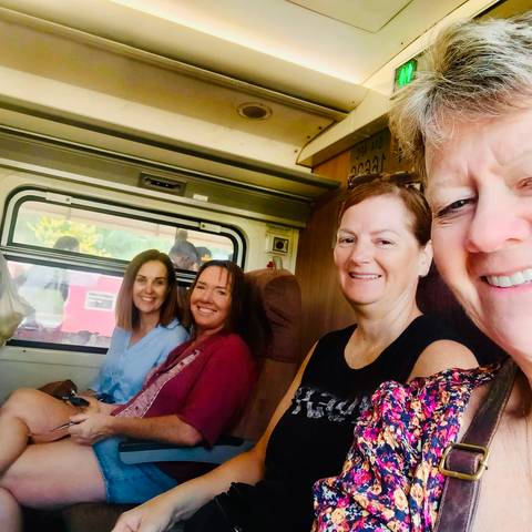 Group of women sitting inside a train carriage during a journey.