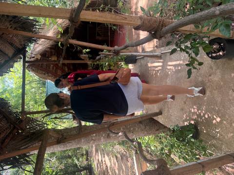 Tourist walking along a narrow shaded walkway into a thatched jungle hut.