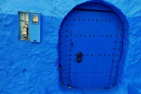Vivid blue plastered doorway with metal studs in the blue city streets of Chefchaouen.