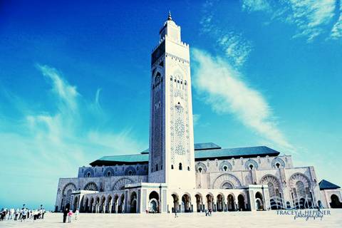 Grand Hassan II Mosque and towering minaret standing against a deep blue sky with wispy clouds.