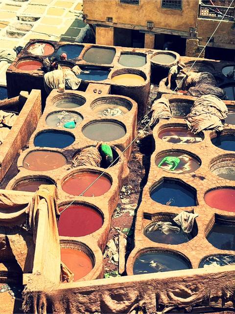 Aerial view of colorful circular dye pits and workers at the traditional leather tanneries of Fes.