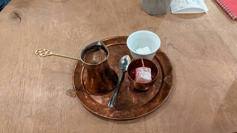 Tray with traditional Bosnian coffee pot, sugar cubes and a piece of Turkish delight on wooden table.